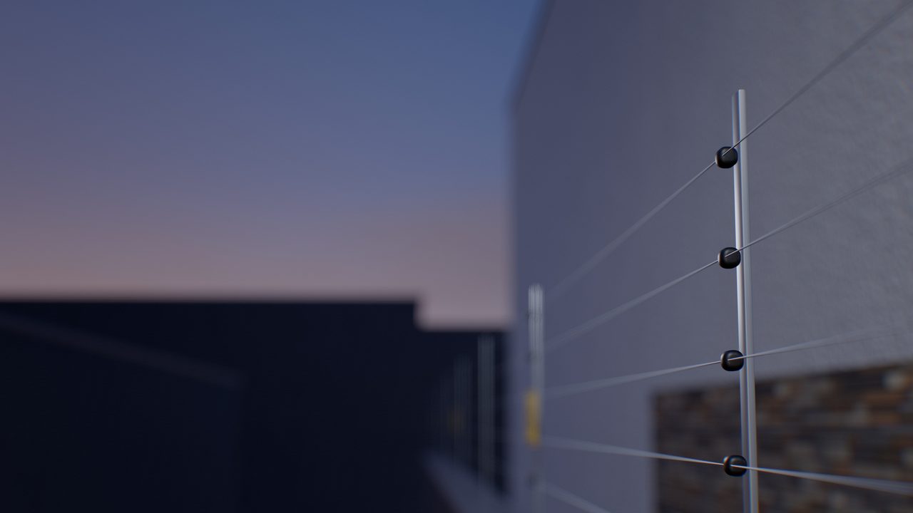 Hastes e fios da cerca elétrica sobre o muro, ao entardecer